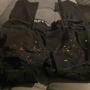 Black distress jeans yellow and red paint splashes all the way down the legs